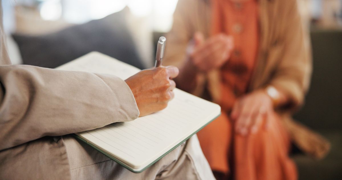 A counselor takes notes during an appointment with a client.