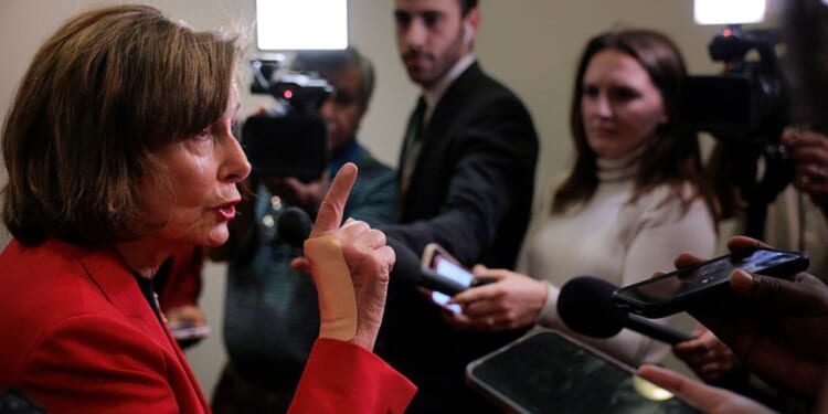 Rep. Nancy Pelosi, a Democrat from California, talks to reporters in the hallway outside of a House Democratic caucus meeting at the U.S. Capitol Visitors Center Wednesday in Washington, D.C.