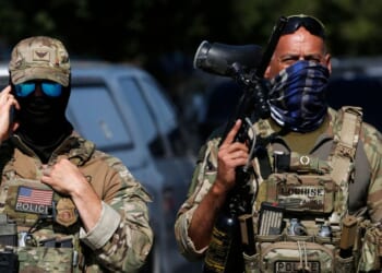 A masked U.S. Customs and Border Protection agent is seen as residents of Chicago's Brighton Park neighborhood confront law enforcement at a gas station after Immigration and Customs Enforcement agents allegedly detained an unidentified man riding in his car, in Chicago, Illinois, on Oct. 4, 2025.