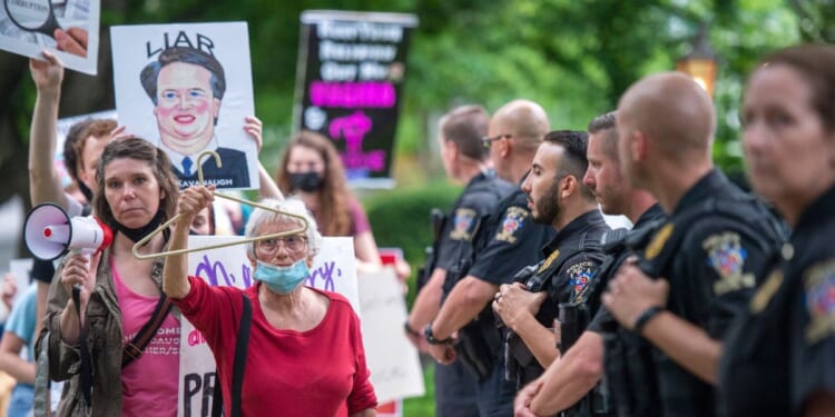 Police officers look on as abortion rights advocates hold a demonstration outside the home of U.S. Supreme Court Justice Brett Kavanaugh on May 18, 2022, in Chevy Chase, Maryland.