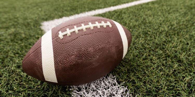 A football sits on a field in a stock photograph.