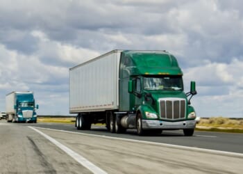 A green truck driving on Interstate 5 in California.