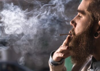 A close up of hipster man smoking weed cigarette.
