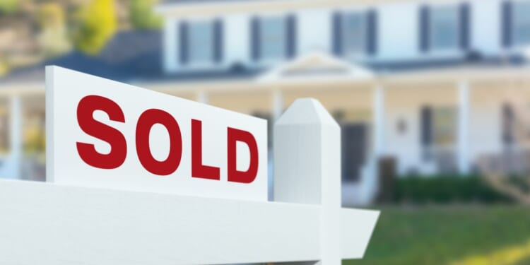 This stock image shows a home with a "Sold" sign in the front yard.