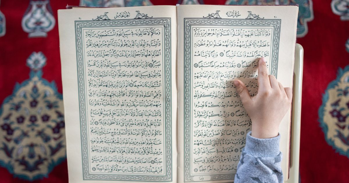 A close up of a boy reading the Quran.