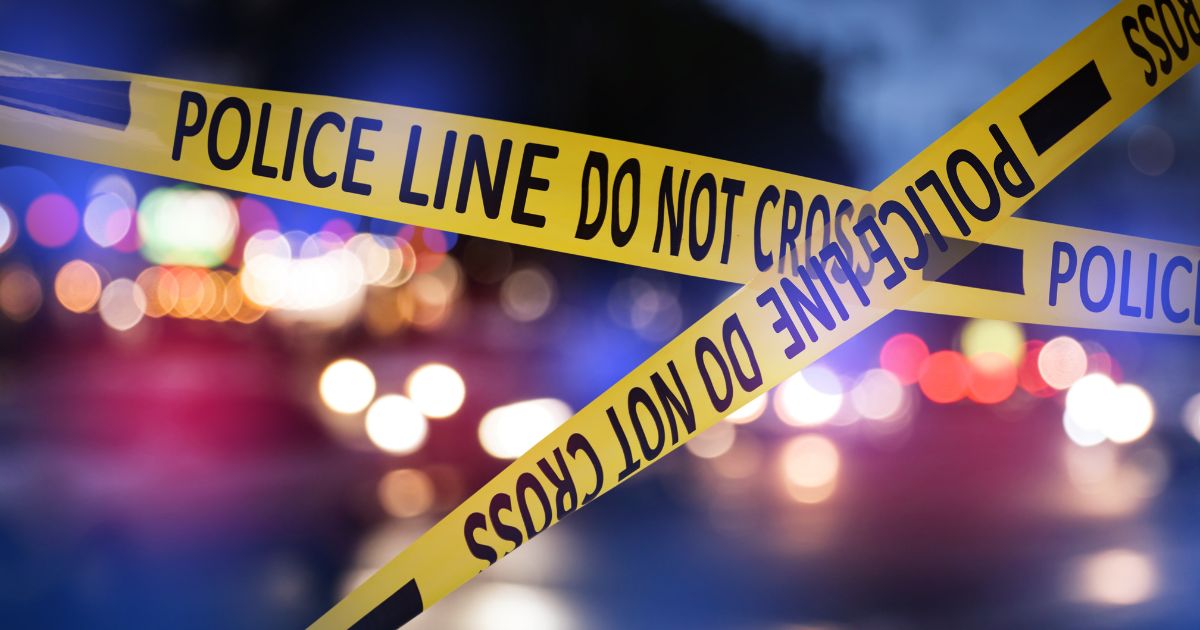This Getty stock image shows police tape in the foreground of a crime scene at night.