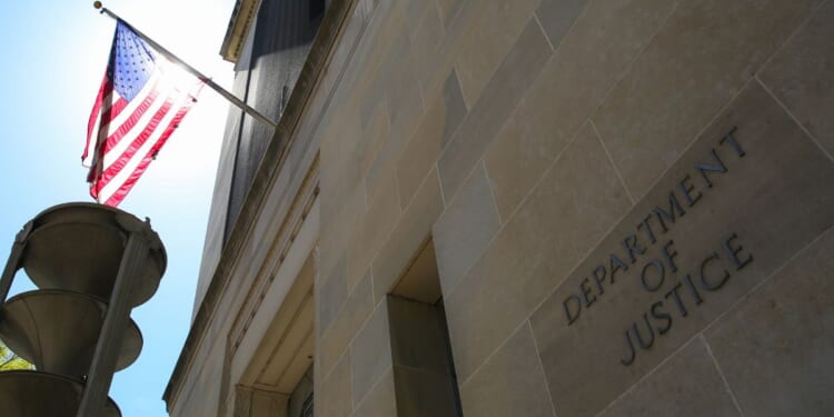 The US Department of Justice building and the American flag stand in the sun in Washington, DC.
