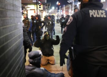A protester on the ground raises his arms as law enforcement officers make arrests after Wednesday declaring an unlawful assembly during an anti-ICE demonstration in Minneapolis outside the Graduate by Hilton Minneapolis.