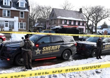 Members of the Hennepin County Sheriff's Office look on as people gather near the scene of a shooting Wednesday by an ICE agent during federal law enforcement operations in Minneapolis, Minnesota.
