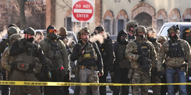 Federal agents stand behind police tape as demonstrators gather near the site of where state and local authorities say a man was shot by federal agents earlier in the morning in Minneapolis, Minnesota, on Jan. 24, 2026.