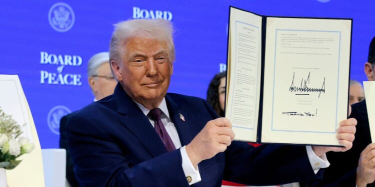 President Donald Trump holds up his signature on the founding charter during a signing ceremony for the “Board of Peace” at the World Economic Forum on Jan. 22, 2026, in Davos, Switzerland.