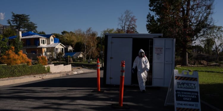 A worker in protective gear exits a storage container at a cleanup site on Dec. 3, 2025, months after the Eaton Fire, in Altadena, California.