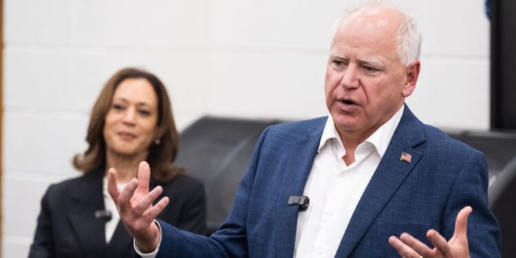 Former Vice President Kamala Harris listens to her running mate, Minnesota Gov. Tim Walz, speak during a visit with members of the marching band at Liberty County High School in Hinesville, Georgia, on Aug. 28, 2024.