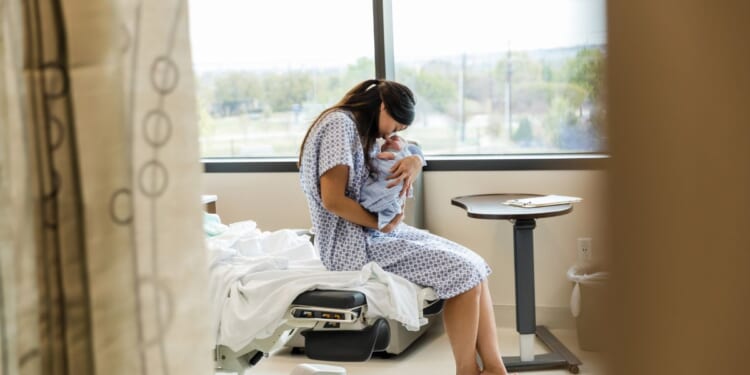 A Chinese mother lovingly holds her newborn baby in a hospital room.