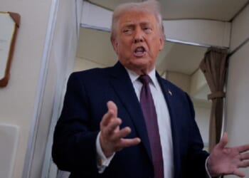 President Donald Trump gestures while talking to reporters Friday aboard Air Force One.