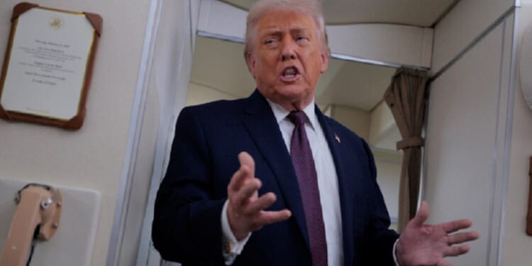 President Donald Trump gestures while talking to reporters Friday aboard Air Force One.