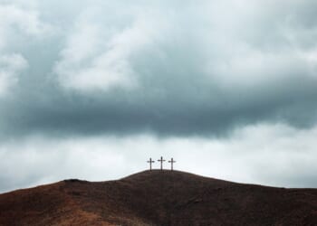 Three crosses line the top of a barren gloomy hill.
