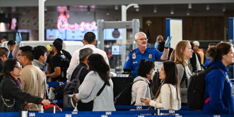 A TSA agent works at a security checkpoint as travelers wait in line at George Bush Intercontinental Airport in Houston, Texas, on Nov. 7, 2025.