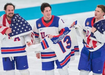 Auston Matthews #34, Zach Werenski #8 and Matthew Tkachuk #19 of Team United States celebrate their team's gold medal victory Sunday in the men`s ice hockey final match between USA and Canada at the 2026 Winter Olympic games in Milan, Italy.