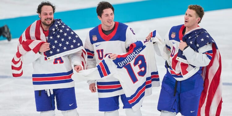 Auston Matthews #34, Zach Werenski #8 and Matthew Tkachuk #19 of Team United States celebrate their team's gold medal victory Sunday in the men`s ice hockey final match between USA and Canada at the 2026 Winter Olympic games in Milan, Italy.