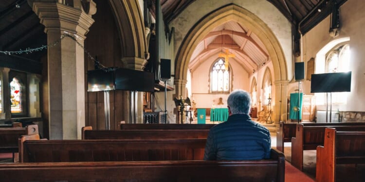 A man sitting in the pews of an Anglican Church.