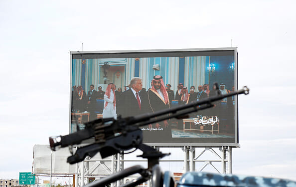 Houthis-mounted machine gun across from screen of Donald Trump meeting with Middle Eastern leaders.