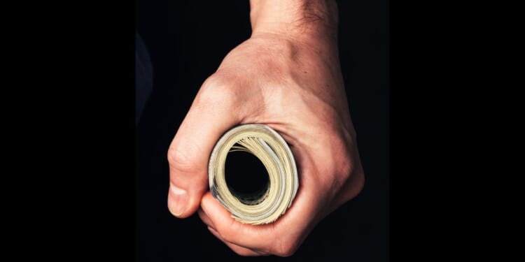 A man holds a wad of cash tightly.