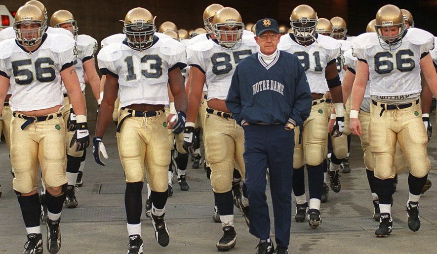 FILE - Notre Dame's head coach Lou Holtz and the Fighting Irish walk onto the field of the Los Angeles Coliseum to warm up for an NCAA college football game against Southern California Saturday, Nov. 30, 1996 in Los Angeles. (AP Photo/Kevork Djansezian, File)