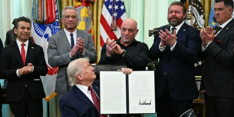 FDA Commissioner Marty Makary, Health and Human Services Secretary Robert F. Kennedy Jr., media personality Joe Rogan, W. Bryan Hubbard, CEO of Americans for Ibogaine, and former Navy SEAL Marcus Lutrell applaud after President Donald Trump signed an executive order in the Oval Office of the White House in Washington, D.C., on April 18, 2026.