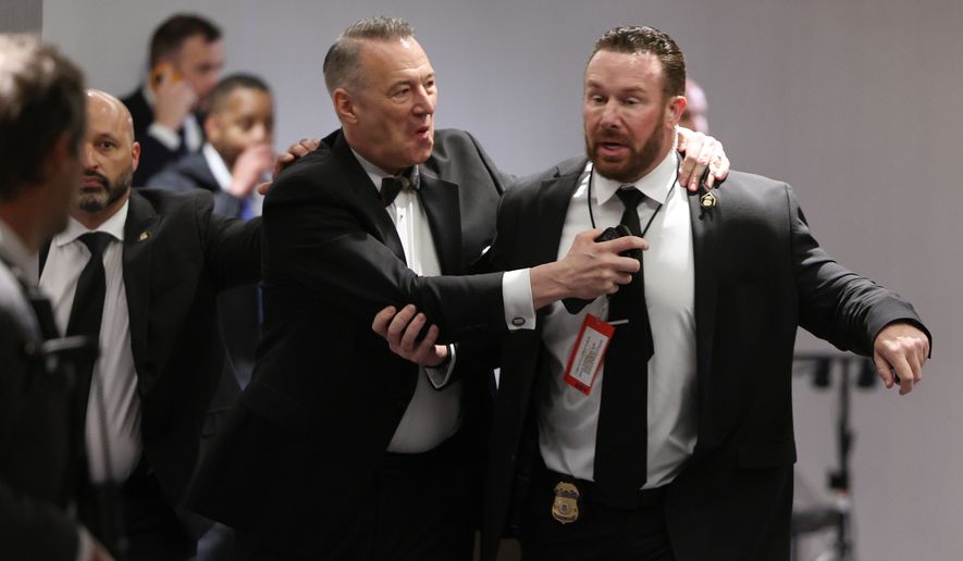 Officers assist guests to exit during the White House Correspondents Dinner, Saturday, April 25, 2026, in Washington. (AP Photo/Tom Brenner)