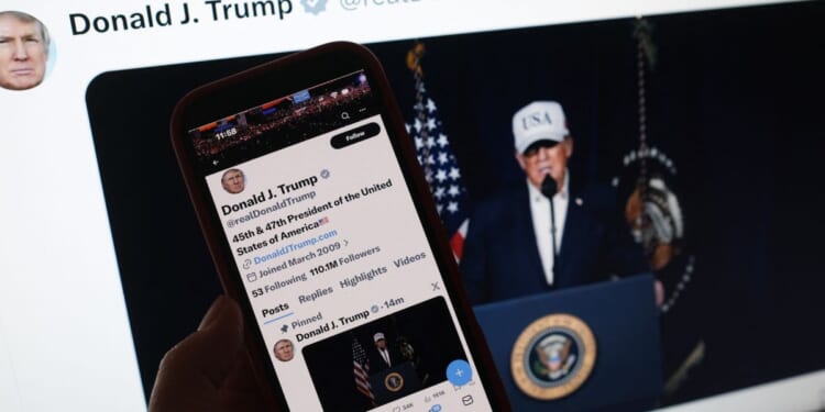 A person looks at President Donald Trump's social media accounts on a computer screen and a phone screen at the same time on Feb. 28, 2026.