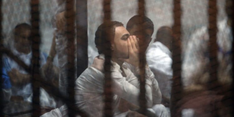 Egyptian defendants await their trial behind the bars of a jail in Cairo on May 30, 2015.