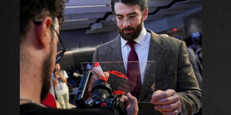Streamer Hasan Piker signs a panel April 7 in front of a camera lens during a campaign event for Abdul El-Sayed, a progressive candidate in the Democratic primary for U.S. Senate in Michigan.