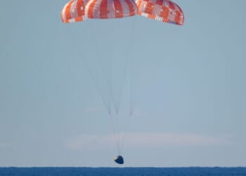 In this handout photo provided by NASA, NASA's Orion spacecraft with Artemis II crewmembers NASA astronauts Reid Wiseman, commander; Victor Glover, pilot; Christina Koch, mission specialist; and Canadian Space Agency astronaut Jeremy Hansen, mission specialist aboard is seen under parachutes as it lands in the Pacific Ocean off the coast of California on April 10, 2026.