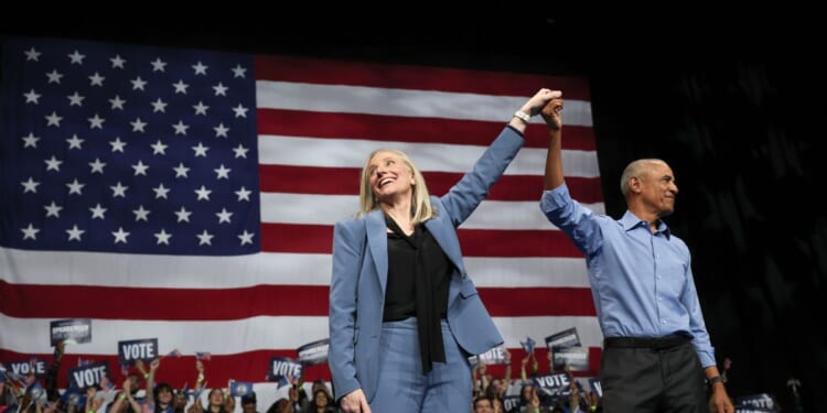 Former President Barack Obama and Virginia Gov. Abigail Spanberger, raise their arms together during a campaign rally in the Chartway Arena on Nov. 1, 2025, in Norfolk, Virginia.