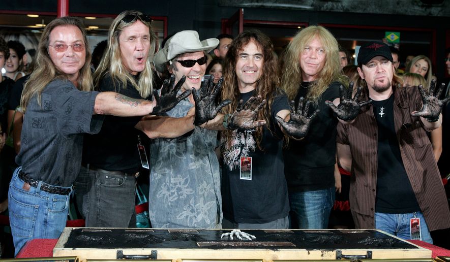 FILE - Members of the British heavy metal band Iron Maiden, from left, Dave Murray, Nicko McBrian, Bruce Dickinson, Steve Harris, Janick Gers and Adrian Smith hold up their hands after being inducted into Hollywood's Rockwalk in Los Angeles on Aug. 19, 2005. (AP Photo/Jae C. Hong, File)