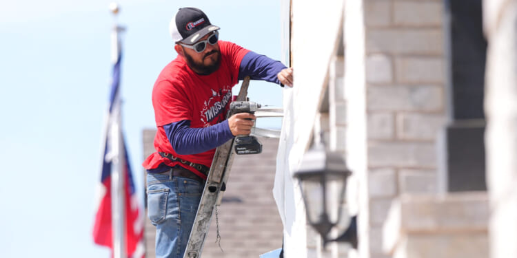 A worker installs a window on a house under construction in Richardson, Texas, on March 23, 2026.