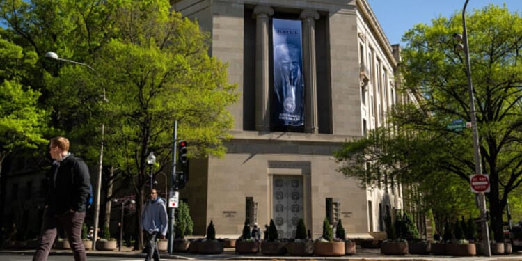 The Department of Justice stands with a poster of Donald Trump hanging from the pillars on April 7, 2026.
