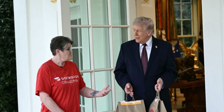 President Donald Trump speaks with a DoorDash delivery worker after she delivered McDonald's at the Oval Office at the White House in Washington, D.C., on April 13, 2026.