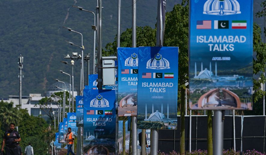 Workers walk past billboards near the Serena Hotel ahead of the second round of negotiations between the U.S. and Iran, in Islamabad, Pakistan, Monday, April 20, 2026. (AP Photo/Anjum Naveed)
