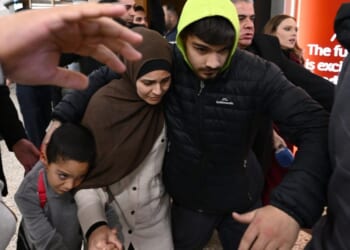 A woman who is accused of ties to the Islamic state is escorted through a crowd by supporters on Thursday, May 7, 2026. (Joel Carrett / AAP Image via AP)