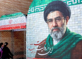 Women walk past a banner depicting Iran's current supreme leader Ayatollah Mojtaba Khamenei along a street Tehran on May 6, 2026.