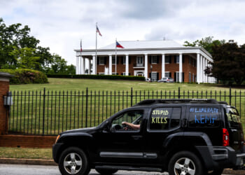 A demonstrator drives past the Governor's Mansion during a drive by protest in Atlanta, Georgia.