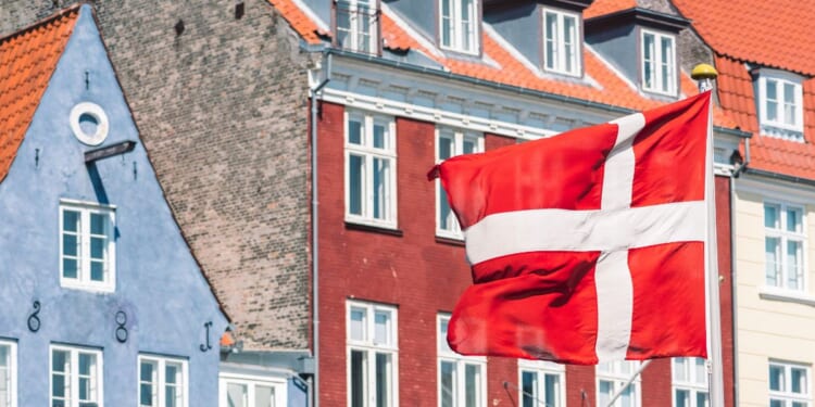 A Danish flag flies in front of traditional houses in Copenhagen.