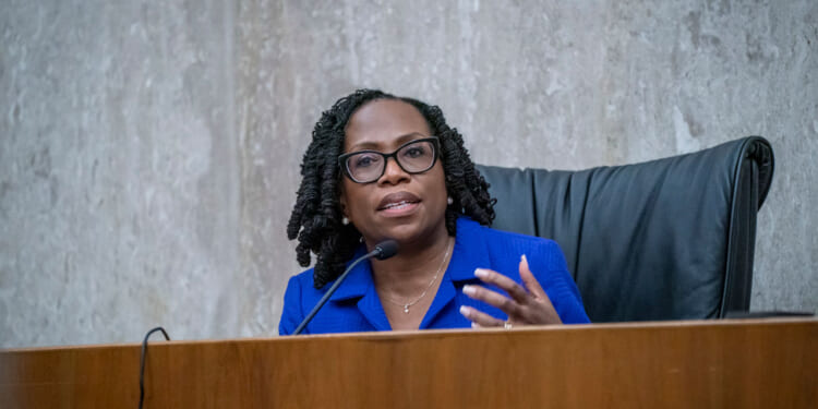 Justice Kentanji Brown Jackson gestures as she sits at a dais.