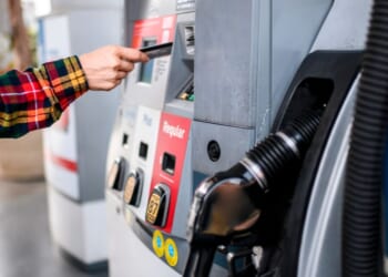 A person pays for gas at a gas station pump using a card.