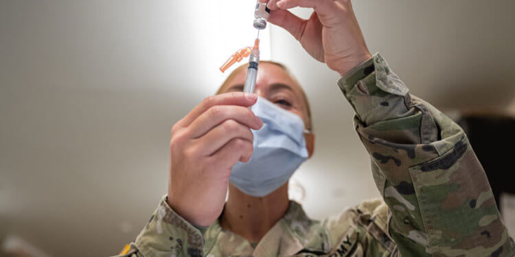A Preventative Medicine Services technician fills a syringe with a Janssen COVID-19 vaccine.