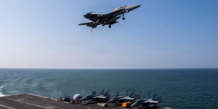 An F/A-18F Super Hornet flies over the flight deck of Nimitz-class aircraft carrier USS Abraham Lincoln in a file photo dated March 6 in the Mediterranean Sea.