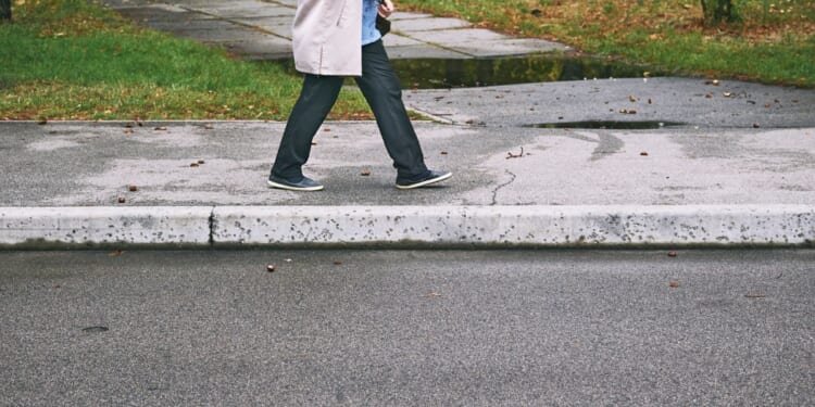 A person walks on a sidewalk during the daytime.