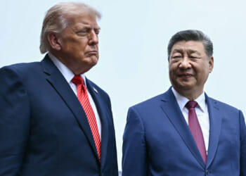 Waist-high shot of President Donald Trump and Chinese President Xi Jinping against a pale blue sky.